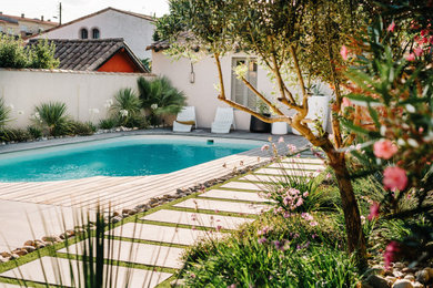 Cette photo montre une très grande piscine arrière exotique sur mesure avec une terrasse en bois.