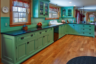 Mid-sized eclectic l-shaped medium tone wood floor eat-in kitchen photo in Providence with beaded inset cabinets, green cabinets, soapstone countertops, green backsplash, wood backsplash, no island, a drop-in sink and black appliances