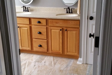 Mid-sized elegant master gray tile travertine floor bathroom photo in Indianapolis with raised-panel cabinets, medium tone wood cabinets, gray walls, an undermount sink, laminate countertops and beige countertops