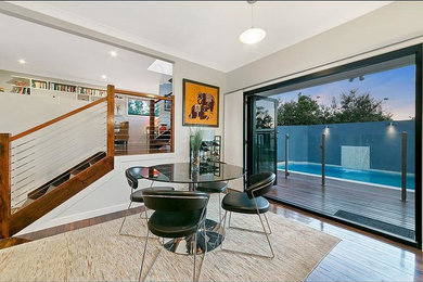 Mid-sized midcentury separate dining room in Brisbane with grey walls, medium hardwood floors and no fireplace.