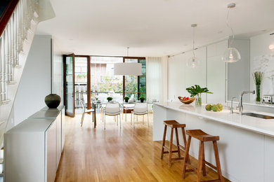 Inspiration for a contemporary medium tone wood floor eat-in kitchen remodel in Boston with an undermount sink, white cabinets, white backsplash, stone slab backsplash, an island and marble countertops