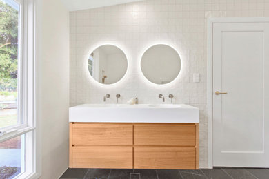Modelo de cuarto de baño doble actual con puertas de armario blancas, suelo de mármol y suelo negro
