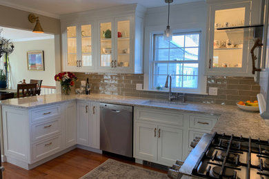 Photo of a medium sized traditional u-shaped kitchen pantry in Burlington with a submerged sink, shaker cabinets, white cabinets, engineered stone countertops, green splashback, metro tiled splashback, stainless steel appliances, medium hardwood flooring, a breakfast bar and beige worktops.