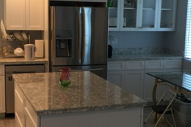 サンディエゴにある中くらいなトラディショナルスタイルのおしゃれなキッチン (シェーカースタイル扉のキャビネット、白いキャビネット、御影石カウンター、無垢フローリング、茶色い床、グレーのキッチンカウンター) の写真