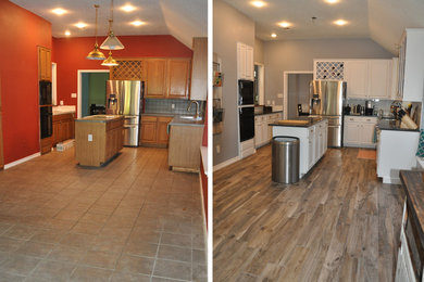 Foto på ett mellanstort vintage svart kök, med en undermonterad diskho, luckor med upphöjd panel, vita skåp, granitbänkskiva, vitt stänkskydd, stänkskydd i tunnelbanekakel, rostfria vitvaror, klinkergolv i porslin, en köksö och brunt golv