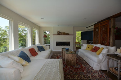 Inspiration for a large eclectic open concept medium tone wood floor and brown floor family room remodel in Boston with beige walls, a standard fireplace, a plaster fireplace and a tv stand