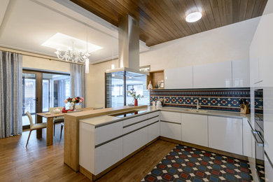 На фото: кухня с плоскими фасадами, белыми фасадами, разноцветным фартуком и полуостровом