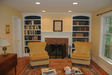 Mid-sized enclosed medium tone wood floor living room library photo in New York with yellow walls, a standard fireplace, a wood fireplace surround and no tv