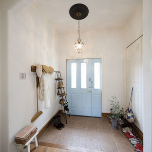 東京23区の片開きドア地中海スタイルのおしゃれな玄関ホール (白い壁、青いドア、茶色い床) の写真