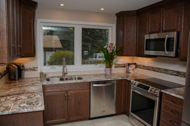 Example of a small classic u-shaped ceramic tile enclosed kitchen design in Edmonton with an undermount sink, recessed-panel cabinets, dark wood cabinets, granite countertops, multicolored backsplash, glass tile backsplash, stainless steel appliances and no island