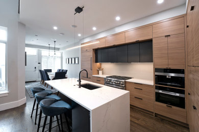 Eat-in kitchen - large modern l-shaped medium tone wood floor and brown floor eat-in kitchen idea in DC Metro with an undermount sink, flat-panel cabinets, light wood cabinets, quartz countertops, white backsplash, glass tile backsplash, black appliances, an island and white countertops