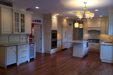 Eat-in kitchen - rustic l-shaped medium tone wood floor eat-in kitchen idea in DC Metro with an undermount sink, raised-panel cabinets, white cabinets, marble countertops, white backsplash, stone slab backsplash, stainless steel appliances and an island