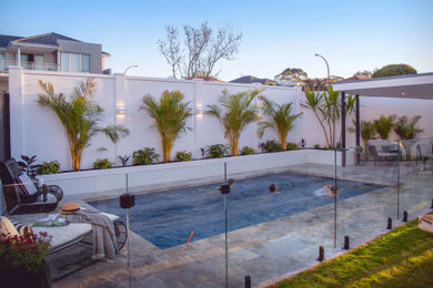 Foto de piscina exótica de tamaño medio rectangular en patio trasero con privacidad y adoquines de piedra natural