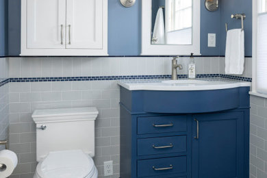Uriges Badezimmer mit blauen Schränken, grauen Fliesen, Metrofliesen, weißer Waschtischplatte und Einzelwaschbecken in Minneapolis