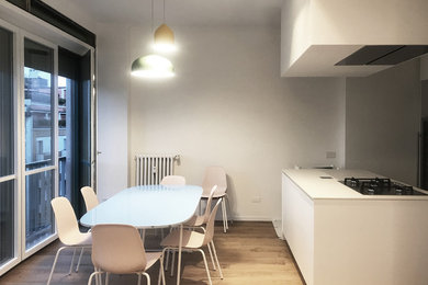 Immagine di una grande sala da pranzo aperta verso la cucina minimal con pareti bianche, parquet chiaro e pavimento beige