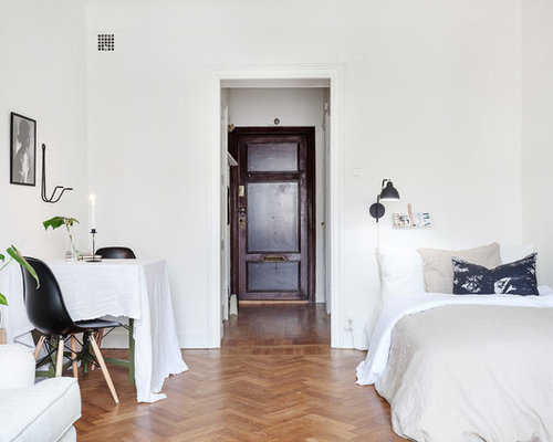 Bild på ett stort nordiskt sovrum, med vita väggar och mellanmörkt trägolv