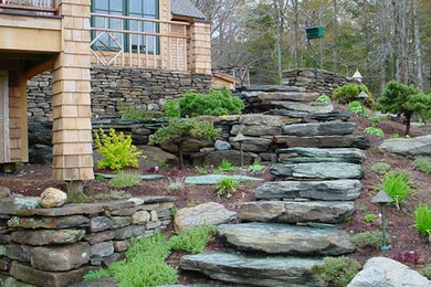 Large arts and crafts backyard full sun formal garden in Burlington with a retaining wall and natural stone pavers.