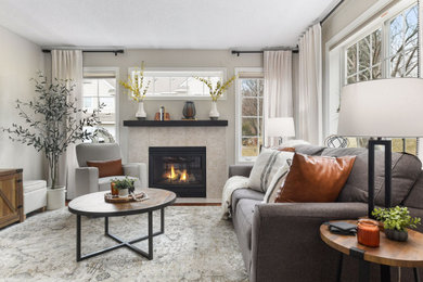 ミネアポリスにある低価格の小さなトランジショナルスタイルのおしゃれなリビング (グレーの壁、ラミネートの床、標準型暖炉、タイルの暖炉まわり、茶色い床、グレーとクリーム色) の写真