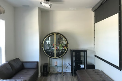 Ejemplo de cine en casa abierto actual pequeño con paredes beige, pantalla de proyección y suelo gris