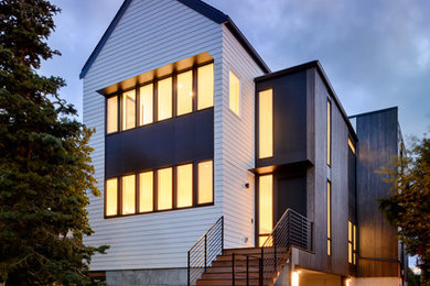 Large contemporary three-storey black house exterior in Seattle with mixed siding, a flat roof and a mixed roof.