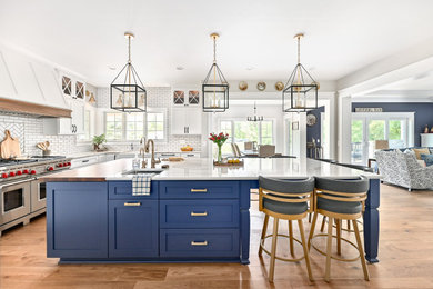 Inspiration for a huge transitional u-shaped vinyl floor and brown floor eat-in kitchen remodel in Milwaukee with a farmhouse sink, shaker cabinets, blue cabinets, quartzite countertops, white backsplash, subway tile backsplash, stainless steel appliances, an island and white countertops