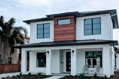 Photo of a large contemporary two-storey stucco white house exterior in Orlando with a hip roof and a mixed roof.