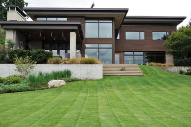 Example of a large minimalist brown two-story wood flat roof design in Seattle