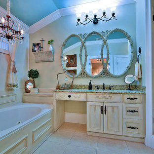 Ejemplo de cuarto de baño principal, tradicional renovado, grande, con armarios tipo mueble, puertas de armario con efecto envejecido, encimera de granito, jacuzzi, ducha esquinera, baldosas y/o azulejos beige, baldosas y/o azulejos de porcelana, paredes beige y suelo de travertino