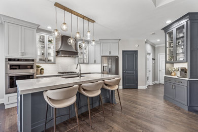 Mid-sized transitional medium tone wood floor and brown floor kitchen photo in Other with an undermount sink, recessed-panel cabinets, quartz countertops, white backsplash, subway tile backsplash, stainless steel appliances, an island and white countertops