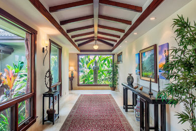 Photo of an expansive tropical hallway in Hawaii with white walls and limestone floors.