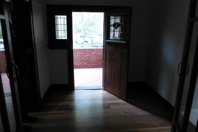 Diseño de distribuidor actual de tamaño medio con paredes blancas, suelo de madera oscura, puerta simple y puerta de madera oscura