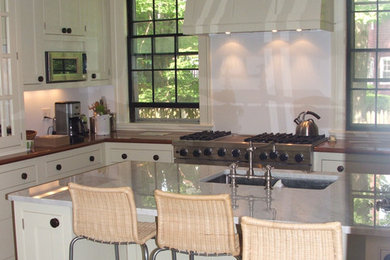 Example of a large u-shaped dark wood floor enclosed kitchen design in Boston with an undermount sink, shaker cabinets, white cabinets, marble countertops, stainless steel appliances and an island