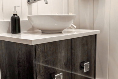 Small beach style light wood floor, brown floor, tray ceiling and wood wall powder room photo in Other with gray cabinets, a vessel sink, quartzite countertops, white countertops and a floating vanity