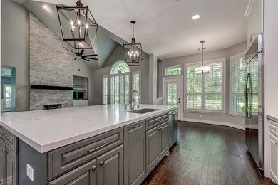 Inspiration for a large transitional l-shaped dark wood floor and brown floor eat-in kitchen remodel in Houston with an undermount sink, raised-panel cabinets, white cabinets, marble countertops, stainless steel appliances and an island
