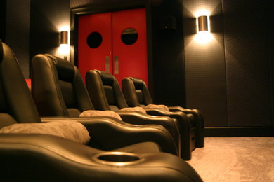 Large contemporary enclosed home theatre in New Orleans with black walls, carpet and grey floor.