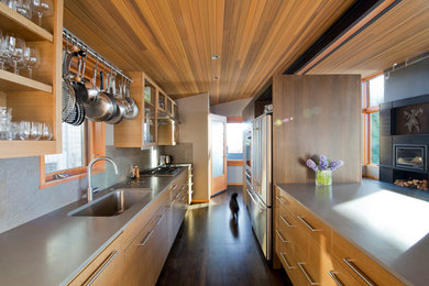 Trendy dark wood floor open concept kitchen photo in Seattle with an undermount sink, flat-panel cabinets, medium tone wood cabinets, quartz countertops, gray backsplash, ceramic backsplash, stainless steel appliances and a peninsula