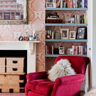 Inspiration for a small eclectic home office in London with pink walls, dark hardwood floors, a standard fireplace, a wood fireplace surround, brown floor and a library.