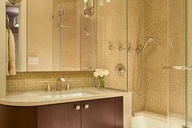 Example of a mid-sized trendy master mosaic tile and brown tile mosaic tile floor and beige floor tub/shower combo design in New York with flat-panel cabinets, an undermount tub, beige walls, dark wood cabinets, an undermount sink, quartz countertops and a hinged shower door