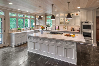 Inspiration for a timeless l-shaped black floor and wood ceiling kitchen remodel in Milwaukee with a farmhouse sink, recessed-panel cabinets, gray cabinets, gray backsplash, subway tile backsplash, stainless steel appliances, an island and gray countertops