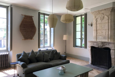 Medium sized open plan living room in Paris with white walls, light hardwood flooring, a standard fireplace, a stone fireplace surround, no tv and brown floors.