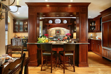 Small elegant u-shaped light wood floor eat-in kitchen photo in New York with an island, an undermount sink, recessed-panel cabinets, medium tone wood cabinets, granite countertops, beige backsplash, stone tile backsplash and stainless steel appliances