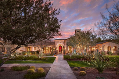 Inspiration for a large mediterranean beige one-story stucco exterior home remodel in Phoenix with a tile roof