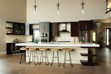 Open concept kitchen - modern l-shaped medium tone wood floor and brown floor open concept kitchen idea in Other with recessed-panel cabinets, dark wood cabinets, beige backsplash, stainless steel appliances, an island, an undermount sink, quartz countertops, stone tile backsplash and white countertops