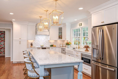 Inspiration for a mid-sized timeless l-shaped medium tone wood floor and brown floor open concept kitchen remodel in Raleigh with a farmhouse sink, shaker cabinets, white cabinets, quartz countertops, white backsplash, porcelain backsplash, stainless steel appliances, an island and white countertops