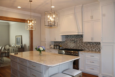 Inspiration for a mid-sized transitional u-shaped medium tone wood floor and brown floor eat-in kitchen remodel in New Orleans with recessed-panel cabinets, white cabinets, granite countertops, beige backsplash, stone tile backsplash and an island