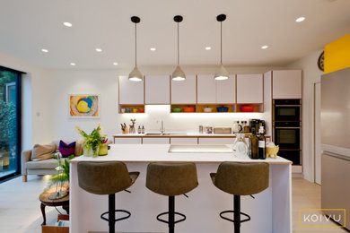 Photo of a large contemporary l-shaped open plan kitchen in London with flat-panel cabinets, white cabinets, laminate countertops, stainless steel appliances, ceramic flooring, an island, beige floors and white worktops.