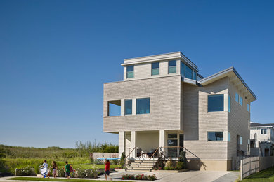 This is an example of a beach style three-storey grey exterior in Philadelphia with wood siding and a flat roof.