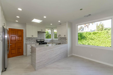 Inspiration for a mid-sized transitional u-shaped porcelain tile open concept kitchen remodel in Los Angeles with a double-bowl sink, shaker cabinets, white cabinets, quartz countertops, beige backsplash, matchstick tile backsplash, stainless steel appliances and an island