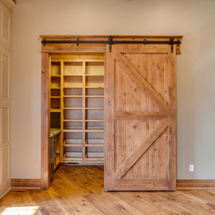 Cette image montre une très grande arrière-cuisine chalet en U avec un évier de ferme, un placard à porte affleurante, des portes de placard beiges, un plan de travail en granite, un électroménager en acier inoxydable, un sol en bois brun et un îlot central.