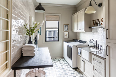Inspiration for a large cottage galley ceramic tile and multicolored floor dedicated laundry room remodel in Little Rock with a farmhouse sink, shaker cabinets, quartz countertops, white backsplash, subway tile backsplash, beige walls, a side-by-side washer/dryer and brown countertops